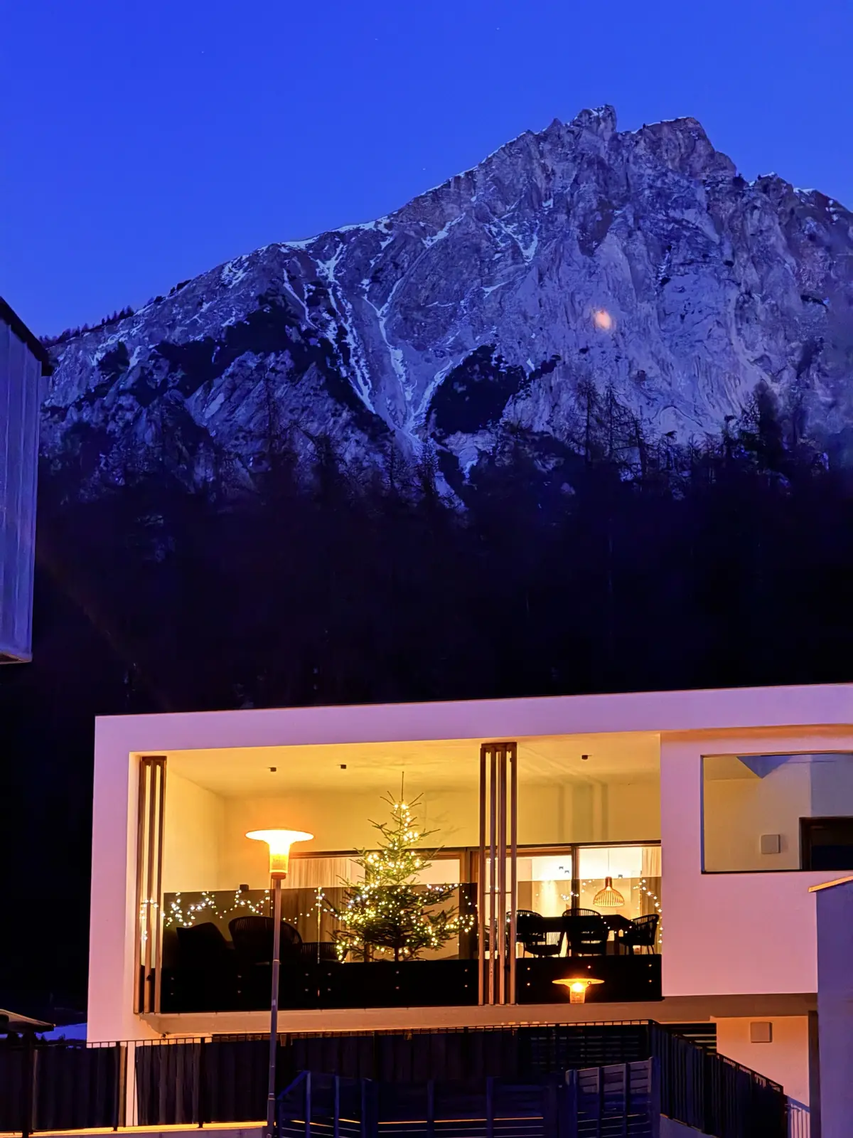 La casa all'ora blu, terrazza illuminata con albero di Natale, sullo sfondo la montagna